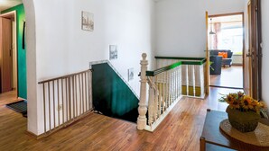 Eine Treppe mit weißen Balustraden und einem mit Grünem Teppich belegten Podest.