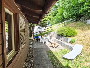 A covered outdoor seating area with tables and chairs, a fire pit, and a view of a hillside. - Crap Grisch by Interhome (Laax)