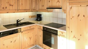 A kitchen with wooden cabinets, a dishwasher, an oven, a coffee maker, and a stovetop.