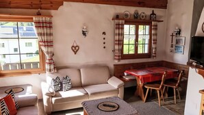 A cozy living room with a sofa, a wooden table, and a television. - Muotta Sulegl 4 by Interhome (Laax)