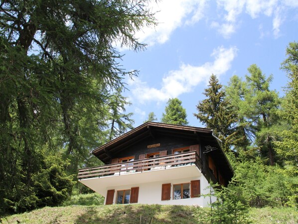 A chalet with a balcony, surrounded by trees and a clear sky. - Chalet Soldanella (BEL205) by Interhome (Bellwald)