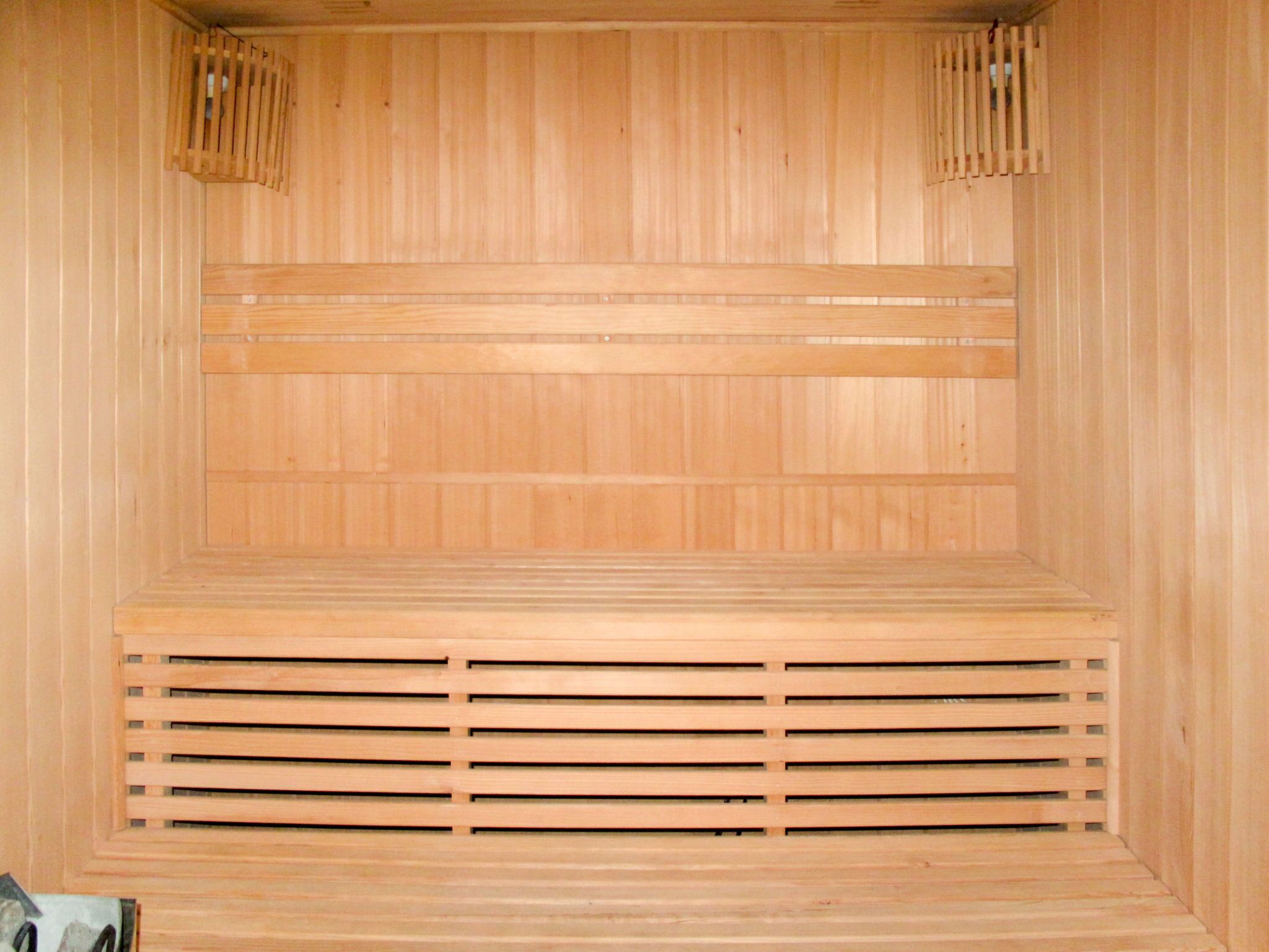 A wooden sauna room with slatted benches and a central ventilation system.
