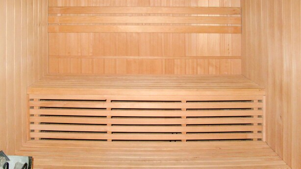Et sauna-rum med trævægge, lamelbænke og et centralt ventilationssystem.