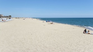 En bred sandstrand med en klar blå himmel.