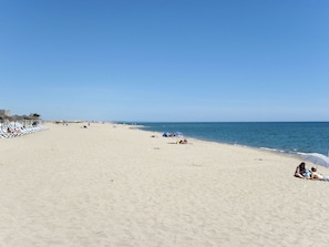 Una amplia playa de arena con cielo azul despejado.
