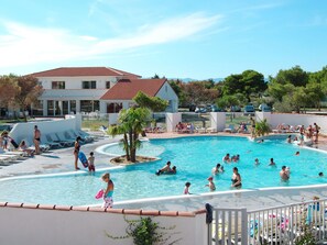 Zona de piscina con sillas de descanso y un edificio al fondo.