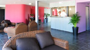 Eine Lobby mit Korbmöbeln, einem Empfangsbereich und einer Pflanze.