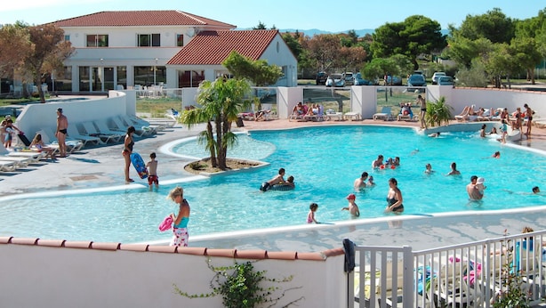 Ein Poolbereich mit Liegestühlen und einem Gebäude im Hintergrund.