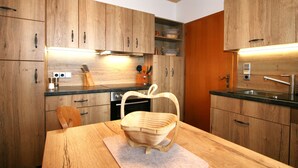Une cuisine moderne avec des meubles de rangement en bois, un plan de travail noir et une table à manger en bois agrémentée d’un panier.