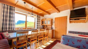 L’intérieur chaleureux d’un chalet comprend un coin repas, un canapé et un téléviseur fixé au mur.