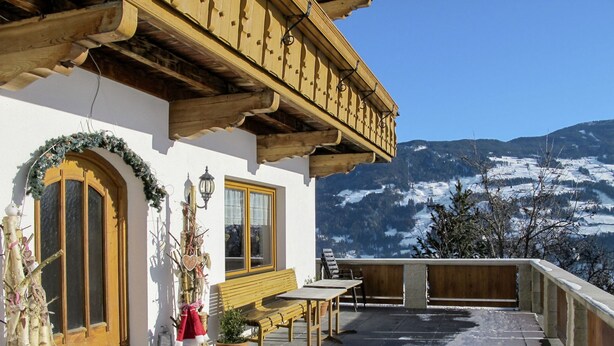 Un balcon en bois offrant une vue sur des montagnes enneigées.