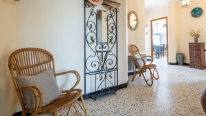 A room with wicker chairs, a decorative metal wall piece, a mirror, and a wooden cabinet. - La Vigneronne by Interhome (Fourques)