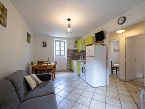 Cozy living space with a kitchenette, dining table, sofa, and washing machine.
