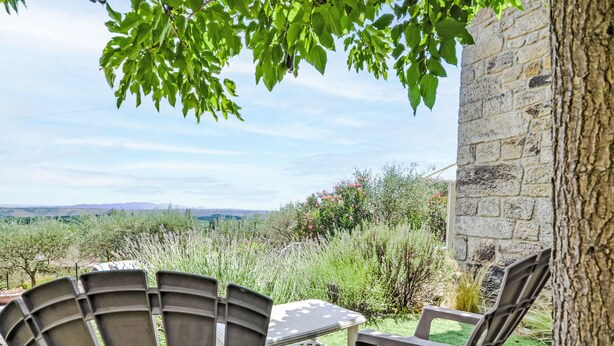 A patio with two chairs and a table, overlooking a scenic landscape with hills and vegetation.