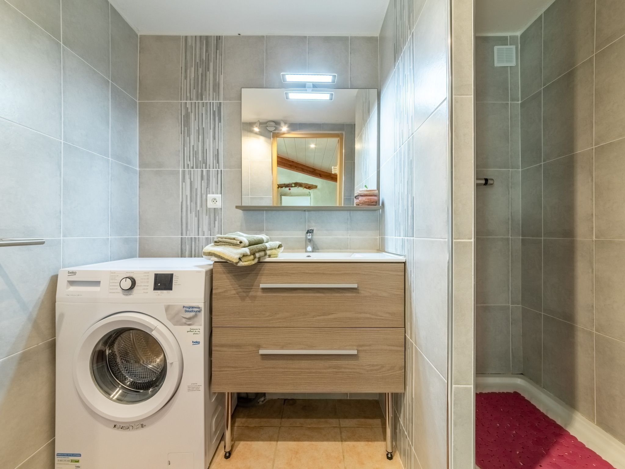 Un baño pequeño con lavadora, lavamanos y espejo.