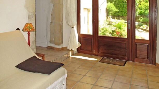 A room with a bed, a lamp, a door leading to a garden, and a tiled floor.