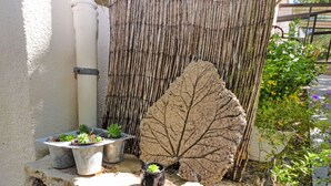 A stone ledge with potted plants and a large leaf sculpture.