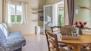 Una habitación acogedora con cama, una mesa de comedor con sillas, televisor y ventana con cortinas.