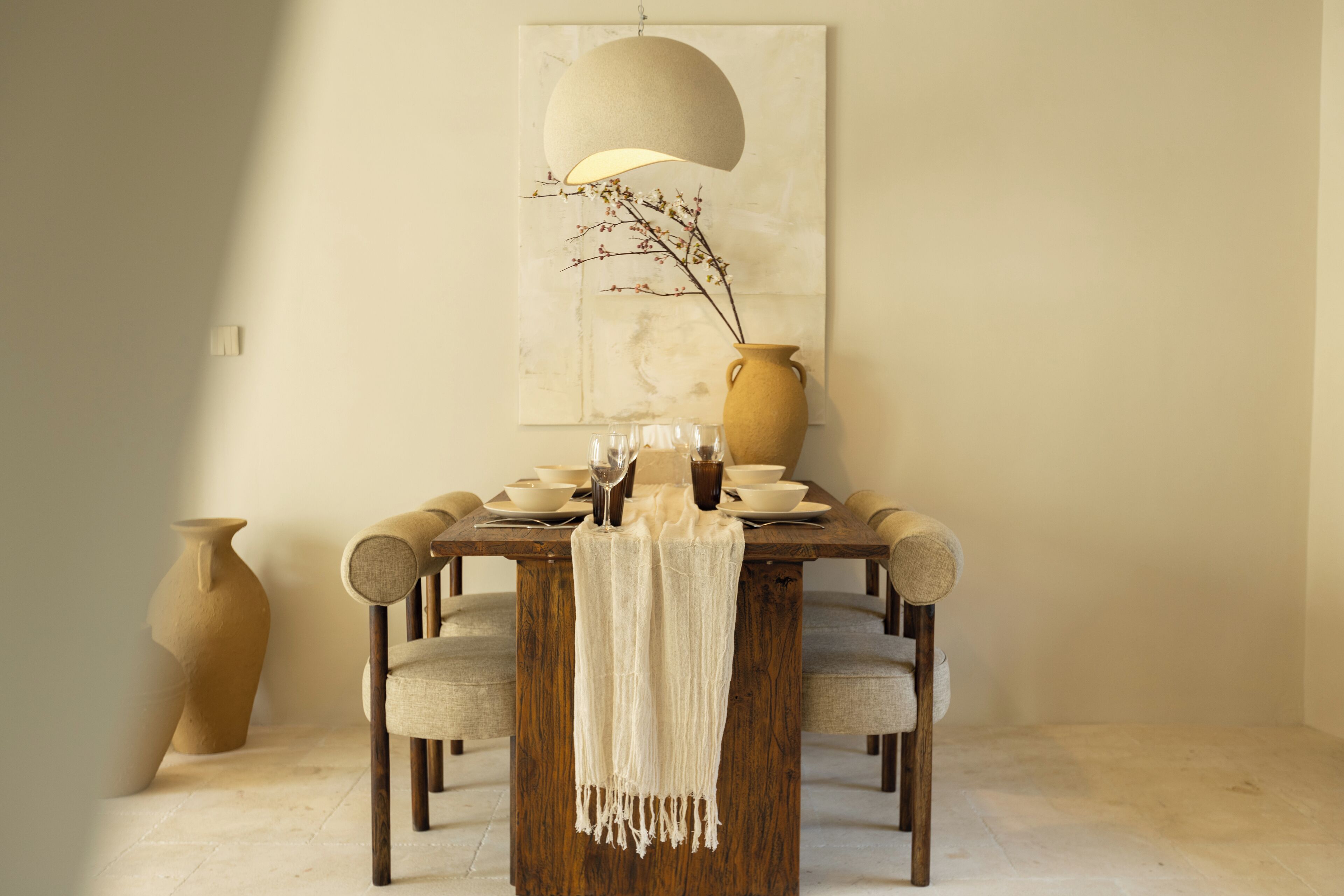 A dining table with chairs, a vase, and a lamp.