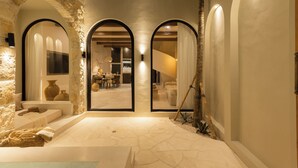 A spacious courtyard with three arched doorways leading to a dining area, surrounded by stone walls and a tiled floor. - Romantic Tropical Villa Sawa  Pererenan (Canggu)