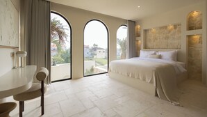 A bedroom with a large bed, a dining table, and a view through arched windows. - Romantic Tropical Villa Sawa  Pererenan (Canggu)