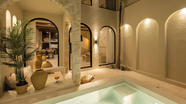 A luxurious indoor pool area with stone arches, a seating area with cushions, and a large potted plant. - Romantic Tropical Villa Sawa  Pererenan (Canggu)