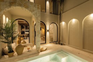 A luxurious indoor pool area with stone arches, a seating area with cushions, and a large potted plant. - Romantic Tropical Villa Sawa  Pererenan (Canggu)