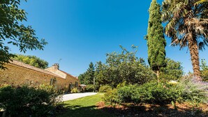 A stone building with a tiled roof, surrounded by lush greenery and a clear blue sky. - Le Coustal by Interhome (Blanquefort-sur-Briolance)