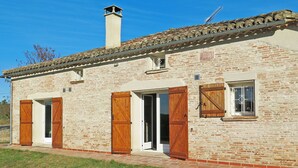 Un edificio rústico de piedra con chimenea, contraventanas de madera y tejado de tejas.