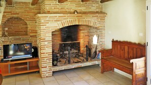 Una sala de estar con chimenea de ladrillo, un televisor sobre un mueble de madera y un banco de madera.