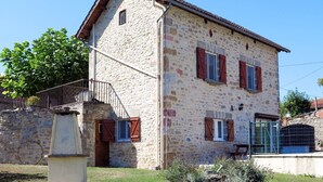A stone building with a sloped roof, multiple windows with shutters, and a small balcony. - Sarrouil by Interhome (Loubressac)