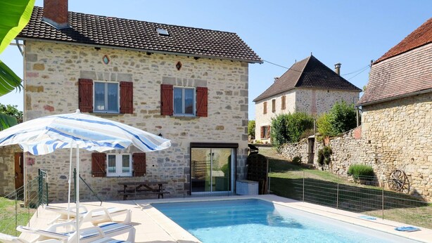 A stone building with a swimming pool, lounge chairs, and a patio umbrella. - Sarrouil by Interhome (Loubressac)