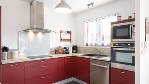 Eine moderne Küche mit roten Schränken, Edelstahlgeräten, einer Mikrowelle, einem Backofen und einer Kaffeemaschine.
