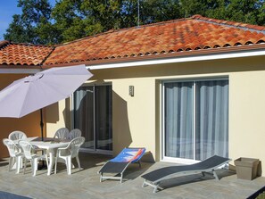 Enjoy a relaxing patio area with a table, chairs, and lounge chair, perfect for outdoor dining and lounging.