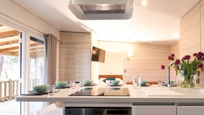 A modern kitchen with a central island, built-in dishwasher, and a large window overlooking a deck. - Premium Key West by Interhome (Ondres)