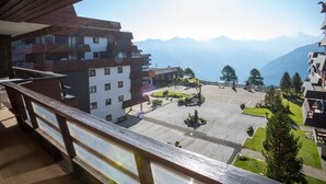 A hotel with a view of mountains, a restaurant, and a courtyard with benches and trees.