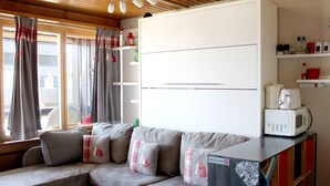 A cozy living area with a sectional sofa, a microwave, and a coffee maker on a counter.