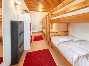 Una habitación con literas, una zona de cocina y una alfombra roja.