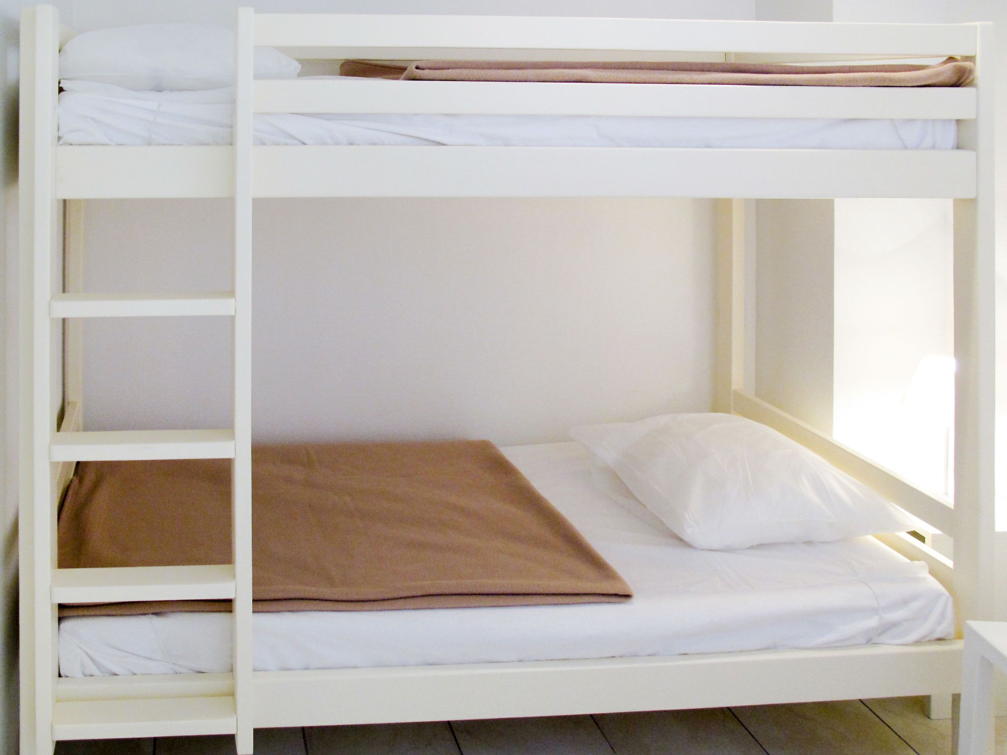 Ein Etagenbett mit weißer Bettwäsche und einer braunen Decke.