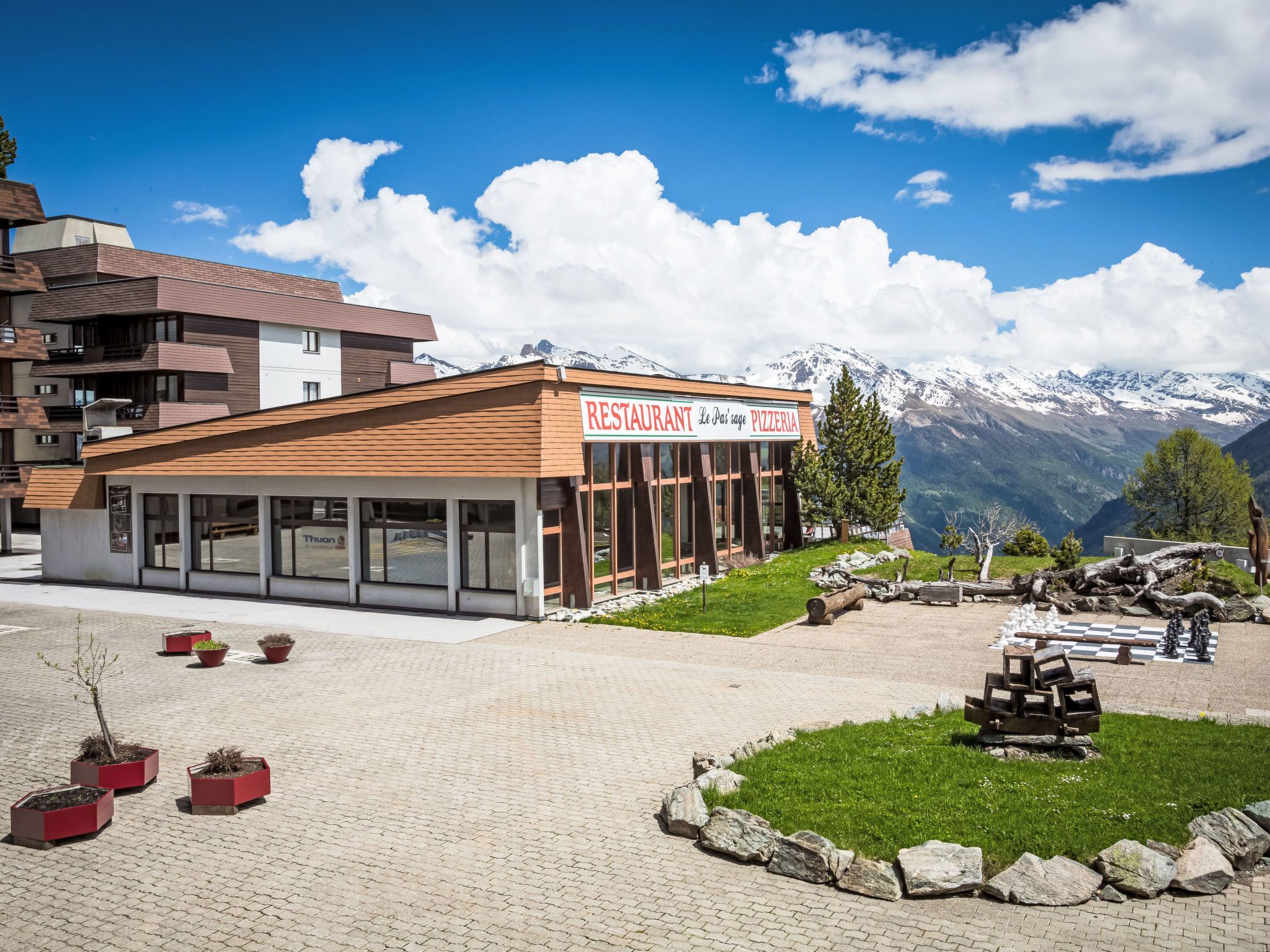 A restaurant with a mountain view, outdoor seating, and a checkered board game.