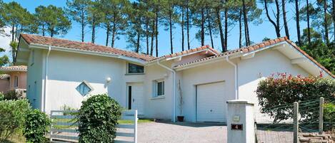 A two-story house with a tiled roof, a garage, and a driveway.