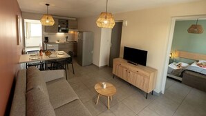 Ein modernes Wohnzimmer mit einer Couch, einem Fernseher und einem Essbereich mit Tisch und Stühlen.