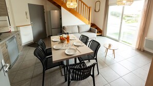 A modern kitchen with a dishwasher, a refrigerator, and a dining area with a table set for two. - Résidence Lagocéan T3 Classic by Interhome (Vieux-Boucau)