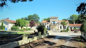 A traditional European-style building with a central entrance, surrounded by a well-maintained garden and a paved driveway.