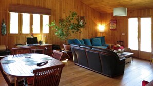 En inredning med trädetaljer, bestående av ett matbord, stolar, en soffa och en krukväxt.