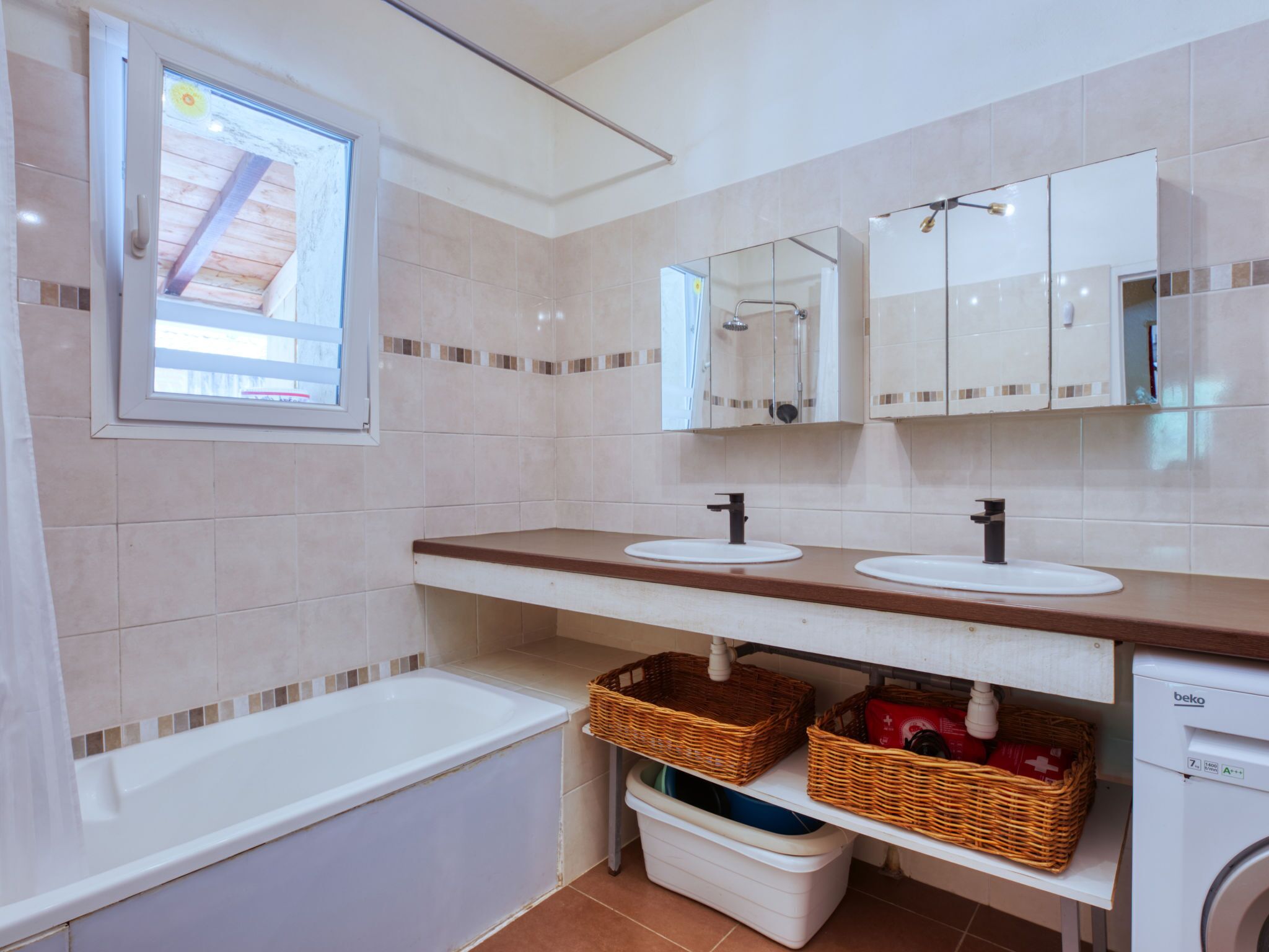 Un baño con una bañera, dos lavamanos, un espejo y una ventana.