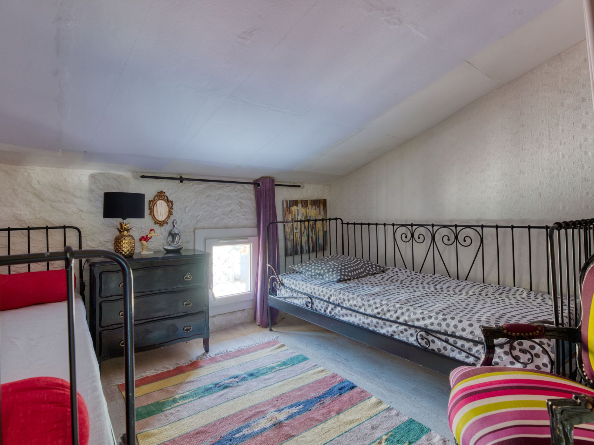 A bedroom with a bunk bed, a dresser, a mirror, and a window with curtains.