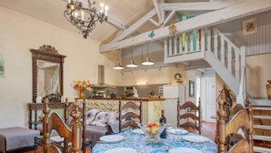 A dining area with a large table set for six, surrounded by wooden chairs. A chandelier hangs from the ceiling, and a staircase leads to an upper level. - Babelle by Interhome (Gaillan-en-Médoc)