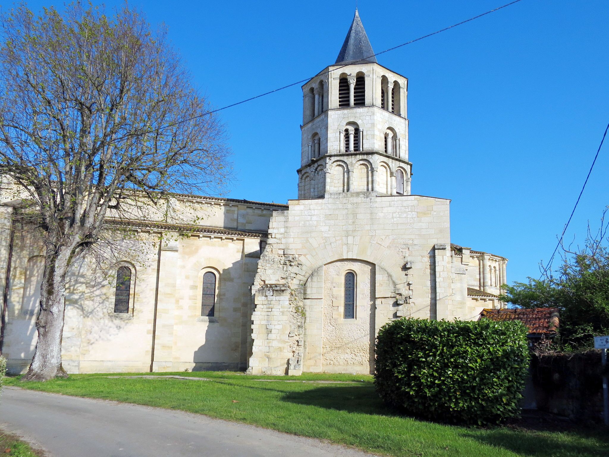 A historic stone building with a bell tower, arched windows, and a grassy area in front.