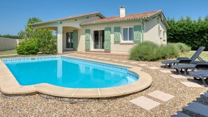 Une maison avec une piscine, un patio couvert et un jardin.